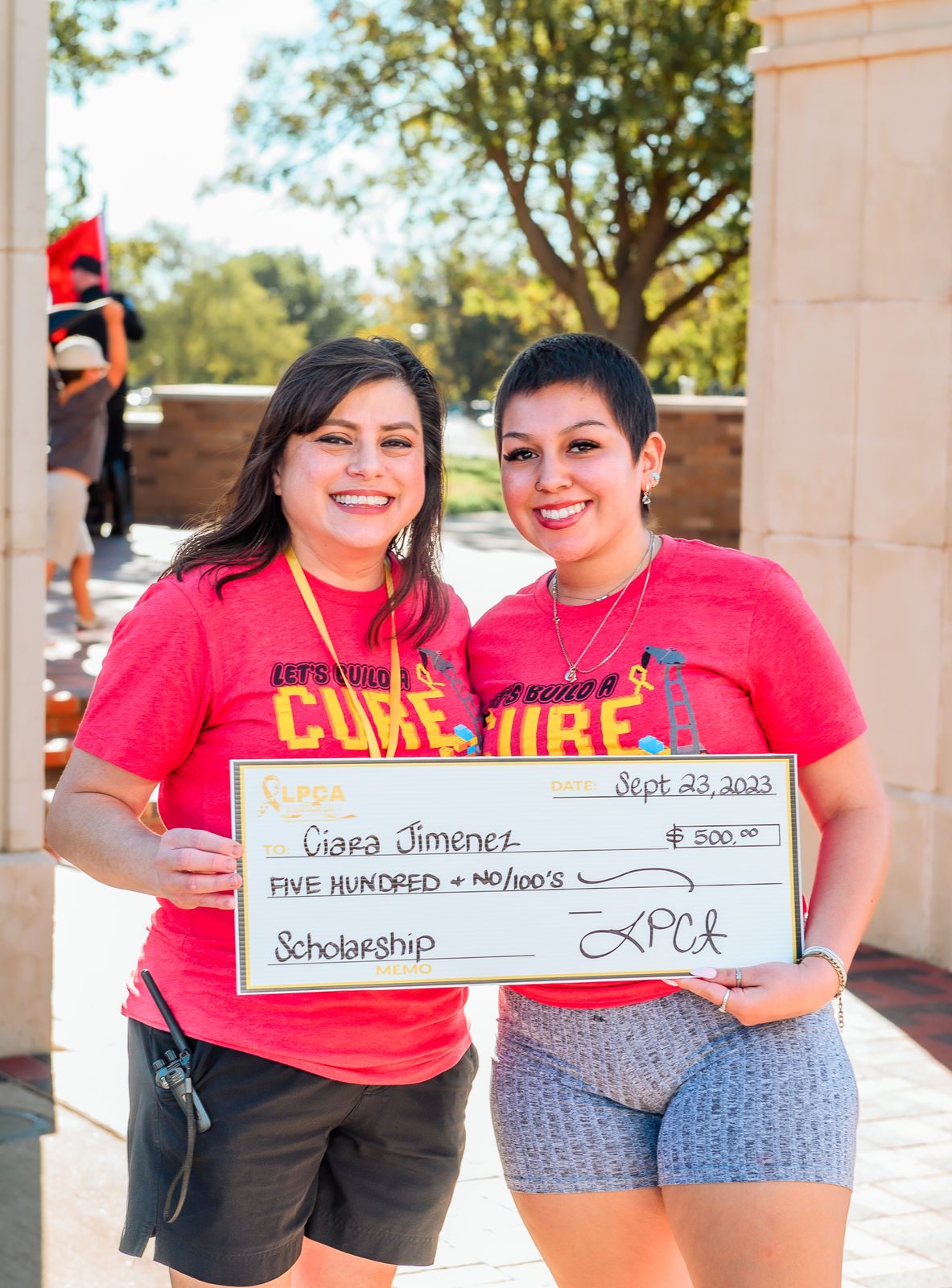 Two women in Lubbock Pediatric Cancer Walk shirts stand together at the walk.